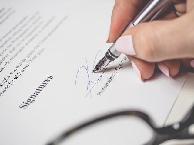 hand holding calligraphy pen signing a leasing document
